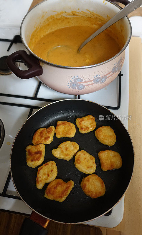 Chicken nuggets being cooked in the pan and Pumpkin velouté in a pot